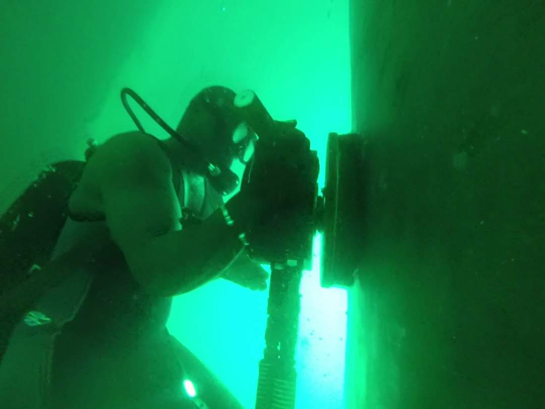 Commercial diver operating a bolt tensioner underwater